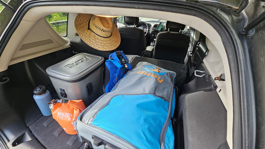 A packed paddleboard in the back of a car.